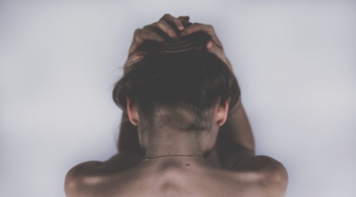 Finding the Best Spine Care Doctor in West Palm Beach | A Practical Guide for Patients Who Want Real Answers Back view of a shirtless person with hands clasped on top of their head, hair gathered underneath.