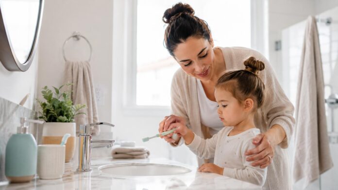 Parent helping young child brush teeth to maintain good dental health